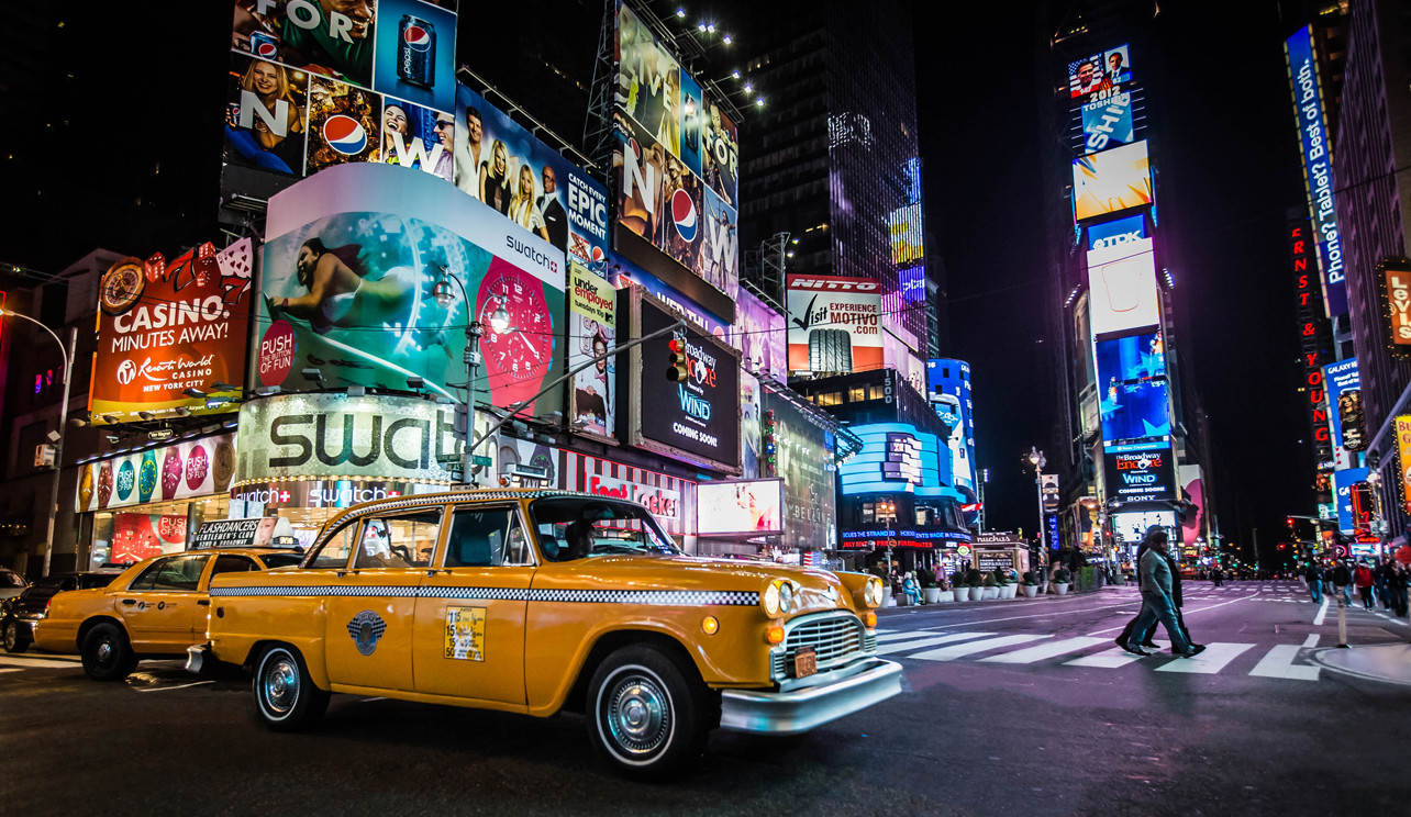 繁華街の真夜中に走るタクシーのイメージ写真